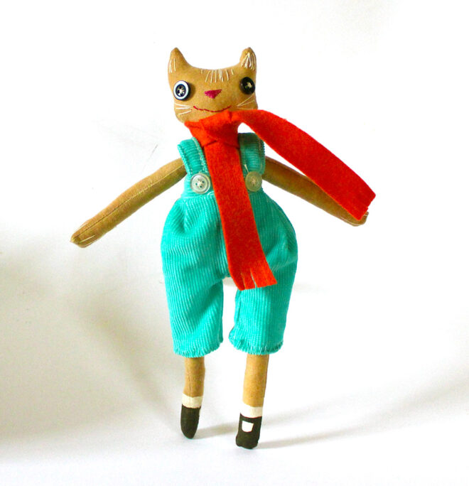 Coffee stained calico cat doll, wearing a pair of turquoise britches.